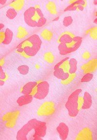 Vaaleanpunaista kangasta, jossa on teksturoitu leopardi-logo pinkin ja keltaisen sävyissä, luoden leikkisän kuvion pyöreistä ja epäsäännöllisistä muodoista.