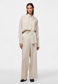 Chemise à rayures beiges à boutons, assortie à un pantalon large à cordon de serrage. Tissu léger au toucher doux.