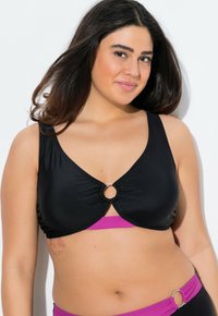 Top de bikini negro con tejido fruncido, detalle de anillo plateado circular en el centro y una banda rosa en la parte inferior. Textura suave, diseño versátil.