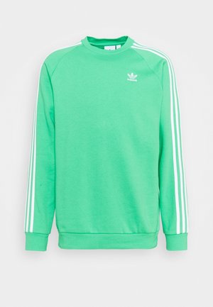 Jasnozielona bluza Adidas z długim rękawem, z białymi paskami na rękawach i małym białym logo Adidas na piersi.