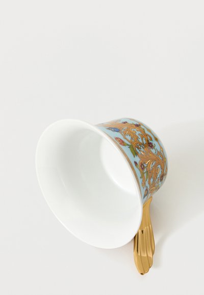 Πορσελάνινο φλιτζάνι τσαγιού με μπλε, χρυσά και ανθικά σχέδια, το οποίο είναι ξαπλωμένο στο πλάι και διαθέτει λαμπερή χρυσή λαβή σε λευκό φόντο.