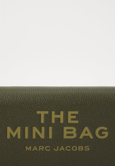 Zelena kožna mini torbica s teksturiranom površinom, sa hrabrim zlatnim natpisom "THE MINI BAG" i "MARC JACOBS."