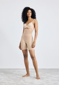 Alusvaatteet bodysuit, jossa on leikkaus yksityiskohtana, säädettävät olkaimet ja puoliväli reittä -pituus. Sileä pinta ja vartalonmyötäinen muotoilu.