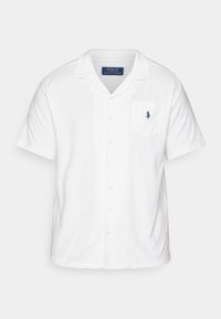Camisa blanca de manga corta con botones, cuello tipo camp collar, bolsillo en el pecho y pequeño logo bordado azul de Polo Ralph Lauren en el bolsillo.