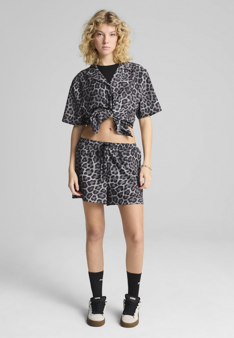 Leopardprint crop top en shorts set in zwart en grijs, met een geknoopte voorkant en een elastische tailleband, gecombineerd met zwarte crew-sokken en sneakers.