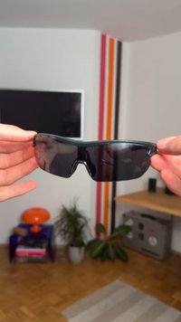 Zwarte sportzonnebrillen met een wraparound ontwerp en getinte lenzen, voorzien van een centrale uitsparing bij de neusbrug en een gladde plastieken montuur.