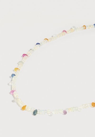 Collier délicat avec de petites perles translucides entrecoupées de pierres précieuses colorées en forme de goutte sur fond blanc.