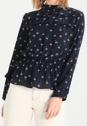 Marineblaue Bluse mit weißem und grünem Blumenmuster, geraffter Taille, langen Ärmeln und einem hohen Kragen mit plissierten Details. Glatte Stoffstruktur.