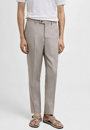 Ljusbeige byxor i slät väv, med flat front, skräddarsydd passform och sidofickor, matchat med bruna sandaler.