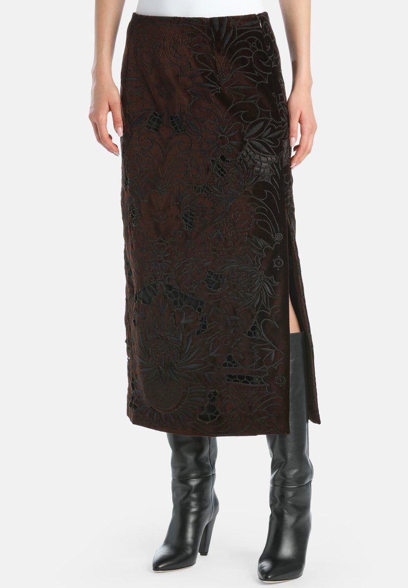 Rjava žametna maxi krila s cvetličnim vezenjem, ki ima stranski razporek in zapletene teksturirane podrobnosti. Nosite jo z črnimi škornji do kolen.