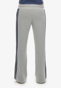 Szare dresy z rozszerzanym krojem, z granatowymi paskami po bokach oraz miękką, elastyczną talią dla wygody. Teksturowany materiał.