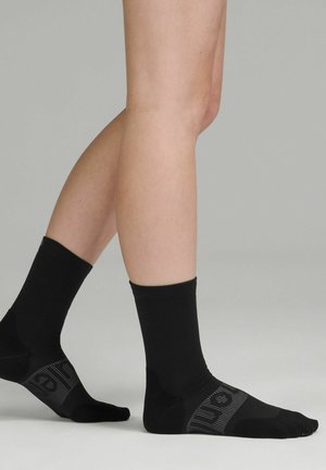 Calze nere alla caviglia realizzate in un materiale liscio, con un bordo testurizzato e un delicato motivo stampato sul risvolto e sulla suola.