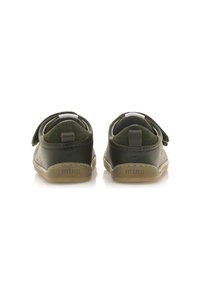 Scarpe in pelle verde scuro con una striscia in velcro, caviglia imbottita morbida e suola in gomma beige. Presentano cuciture decorative e branding sul tallone.