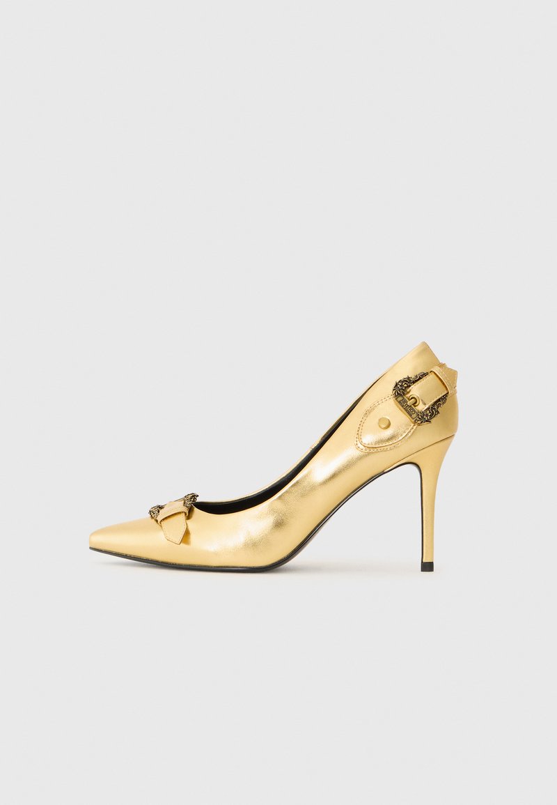Gold leather high heel shoe, pointed toe, featuring a decorative buckle detail on the side and a sleek, glossy finish with a stiletto heel.