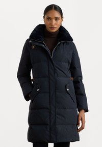 Tamsiai mėlynas pūkinis paltas su dirbtinio kailio apykakle, užtrauktuku ir šoninėmis kišenėmis. Savybės: siuvinėtos detalės ir rudos odos akcentas apykaklėje.