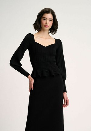 Top in maglia nera a coste con scollatura quadrata, maniche lunghe e orlo a peplum, abbinato a una gonna nera coordinata. Texture liscia su tutta la superficie.