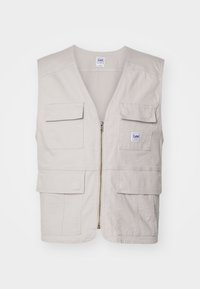 Gilet color crema realizzato in cotone, design senza maniche, dotato di una cerniera frontale e quattro grandi tasche frontali per riporre oggetti.