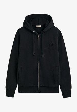 Schwarze Zip-Hoodie aus weichem Stoff. Verfügt über eine Kapuze, Seitentaschen, gerippte Bündchen und ein auf die Brust gesticktes Logo.