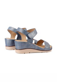 Sandali con zeppa in pelle blu, caratterizzati da una finitura metallica, cinturini regolabili e una soletta testurizzata. Suola curva e dettagli decorativi.