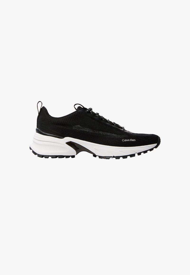 Μαύρο αθλητικό παπούτσι Calvin Klein με λευκή, παχιά σόλα, υφαντό επάνω μέρος με υφή, μαύρα κορδόνια και θηλιές στην φτέρνα και στη γλώσσα.