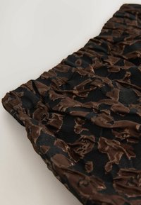 Tessuto nero con un motivo a macchie di leopardo marroni, caratterizzato da una finitura testurizzata. Design arricciato nella parte superiore con elastico per la vestibilità elasticizzata.