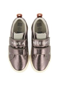 Zapatillas de bronce metálico con cintas de velcro, que presentan el texto "¡QUE TENGAS UN BUEN DÍA!" en la parte superior. Suela de goma de color claro, material texturizado.