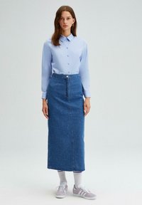 Chemise boutonnée bleu clair, jupe midi en denim avec des embellissements en perles, baskets grises et chaussettes blanches. Tissu lisse, coupe classique.