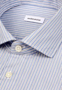 Chemise rayée bleue et blanche avec col boutonné et étiquette de marque « seidensticker » à l'intérieur de l'encolure.