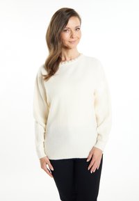 Crème-kleurige trui van zacht, gestructureerd materiaal met een ronde halslijn, versierd met een delicate kraalrand en geribbelde mouwen.