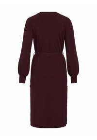 Burgundy långärmad klänning med figurnära midja, sidofickor och ribbade ärmslut. Har en rak fåll och lätta sidoklyftor.