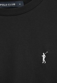 Svart sweatshirt med en texturerad tyg och en liten vit broderad figur som håller ett verktyg på vänster sida av bröstet.