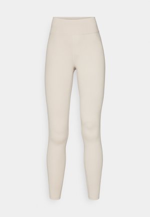 Beige aktive leggings med høj talje, glat tekstur og en tætsiddende pasform. Har minimal syning og ingen synlig branding.