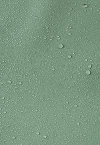 Gouttes d'eau dispersées sur une surface de tissu vert sauge texturé, mettant en évidence sa qualité déperlante.