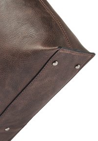 Braune Lederhandtasche mit strukturiertem Oberflächen, robuster Naht und metallischen Hardware-Akzenten in einer klaren Form.