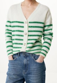 Cárdigan a rayas verdes y blancas con escote en V, botones en la parte delantera y textura suave, combinado con jeans de mezclilla azules.
