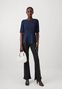 Nāvjnieku pepluma tops, ribots melns platiem izšļorētām biksēm, balta izdūrota soma un purpura papēžu sandales. Gludas faktūras un smalkas detaļas.