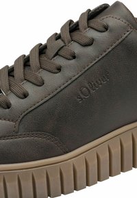 Zapatilla de piel marrón con superficie texturizada, presenta puntera redonda, cordones marrones y una suela de goma chunky beige con diseño estriado.