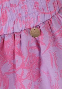 Paarse stof met een bloemenpatroon in roze tinten, geraffineerde taille met een gouden label met de inscriptie "BIZUU," zachte textuur.