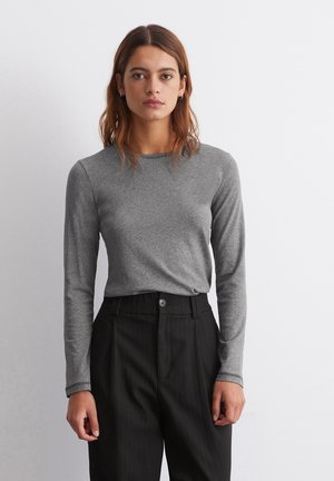 Grijze langemouwen shirt van een zachte stof, met een ronde halslijn en een getailleerde stijl, gecombineerd met zwart gestreepte broek.