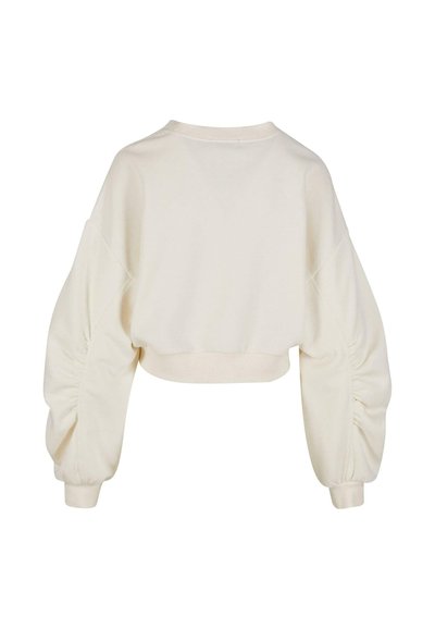 Sweatshirt raccourci en beige clair avec des manches bouffantes et froncées et un ourlet côtelé. Tissu en coton doux au toucher lisse.