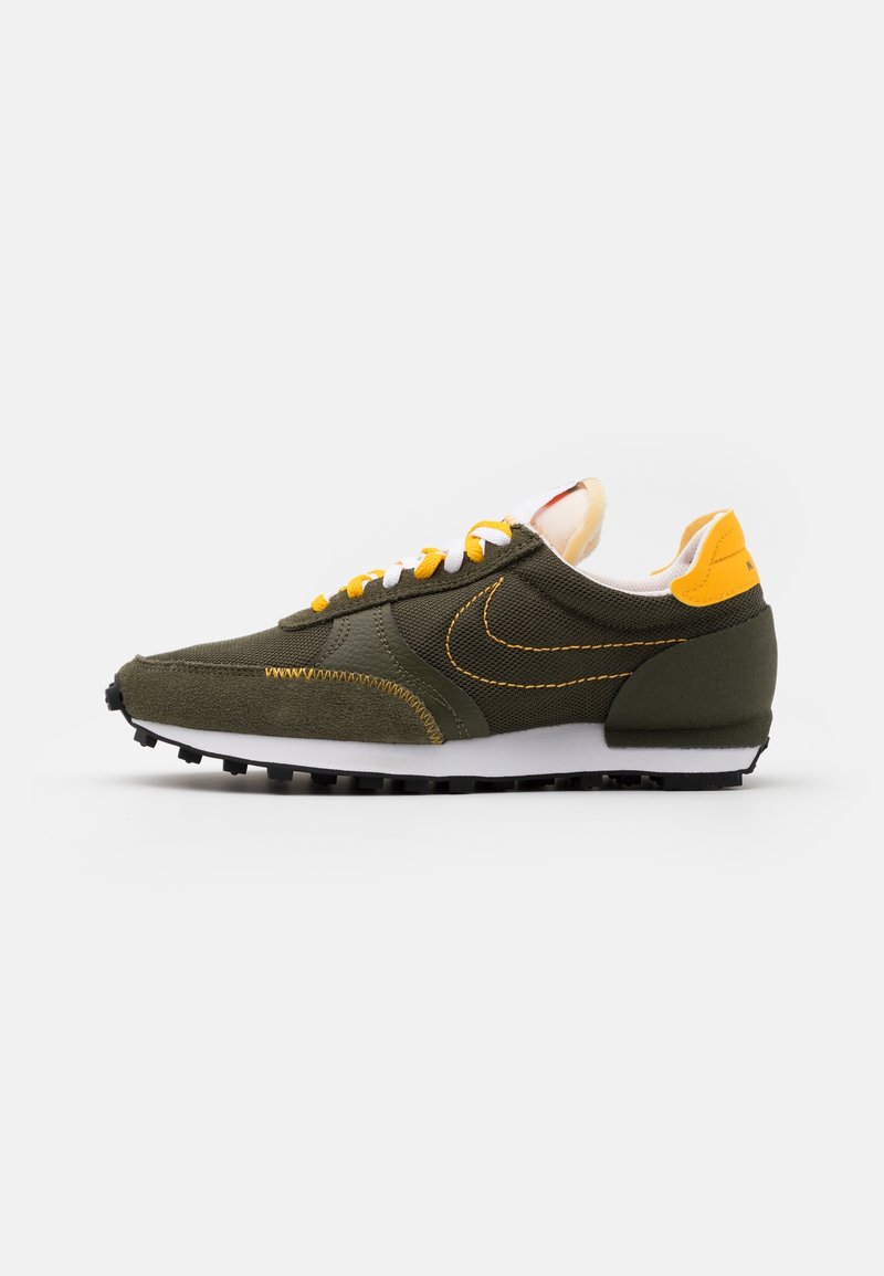 Chaussure de course vert foncé et jaune avec semelle et lacets blancs, dessus en tissu texturé et semelle extérieure en caoutchouc antidérapant, vue latérale sur fond blanc.