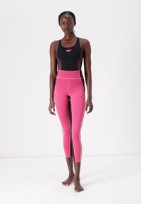 Black swim top with pink accents, paired with high-waisted pink leggings featuring a textured pattern and contrasting side stripes.