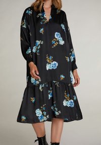 Robe noire à motifs floraux bleus et dorés, avec des manches longues, un décolleté en V et un ourlet en étages. Fabriquée en tissu doux avec une coupe décontractée.