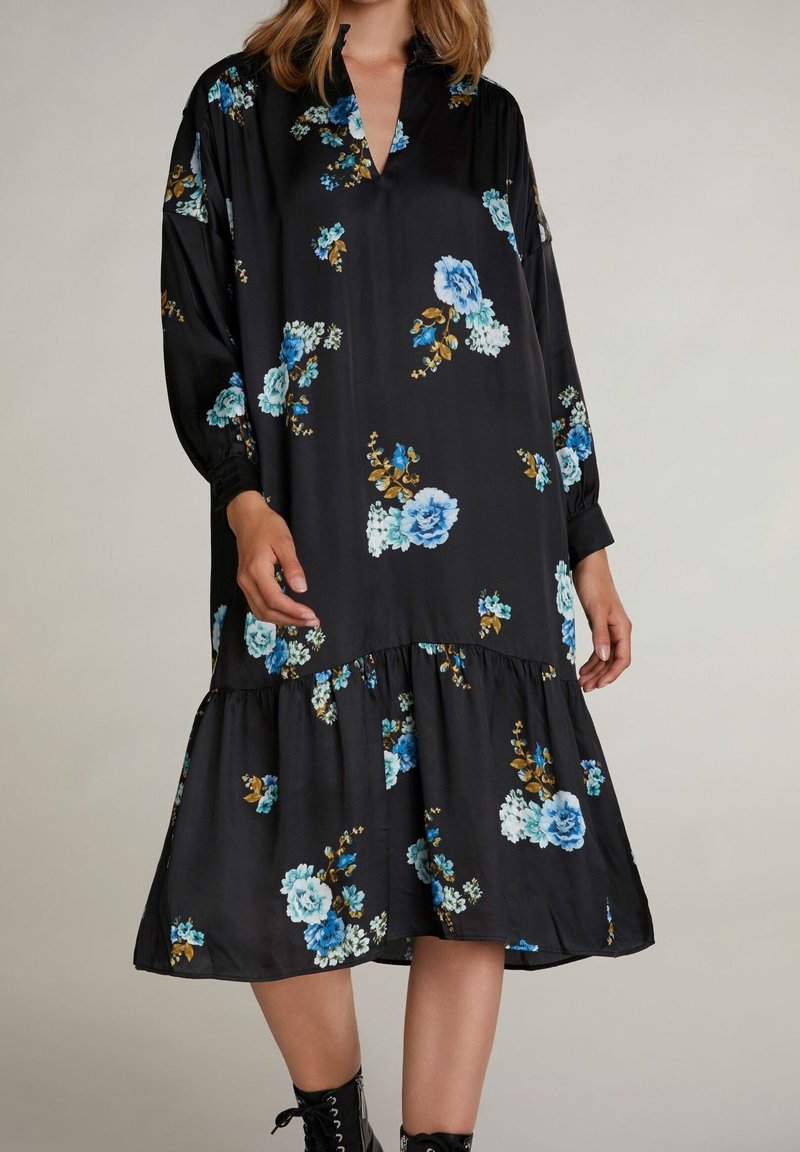 Robe noire à motifs floraux bleus et dorés, avec des manches longues, un décolleté en V et un ourlet en étages. Fabriquée en tissu doux avec une coupe décontractée.