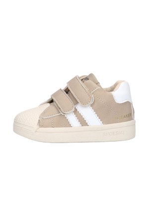 Beige toddler sneaker met witte strepen, dubbele klittenbandriempjes, gestructureerde neuskap en gewatteerde witte hielkraag.
