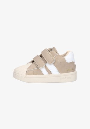 Beige toddler sneaker met witte strepen, dubbele klittenbandriempjes, gestructureerde neuskap en gewatteerde witte hielkraag.