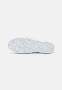 Hvit sneakersåle med intrikate blomster- og svirvelmønstre, teksturert overflate og merkevaren som leser "BOBS."