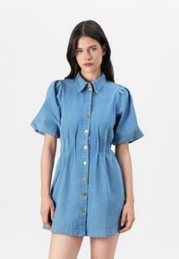 Vestido camiseiro de denim com mangas curtas com volume, fecho de botões e detalhes plissados. Cor azul claro com botões em tom dourado e silhueta ajustada.
