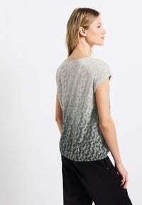 Haut léger gris présentant un motif de pelage animal, des manches courtes et une coupe décontractée avec un effet ombragé allant du gris clair au gris foncé.