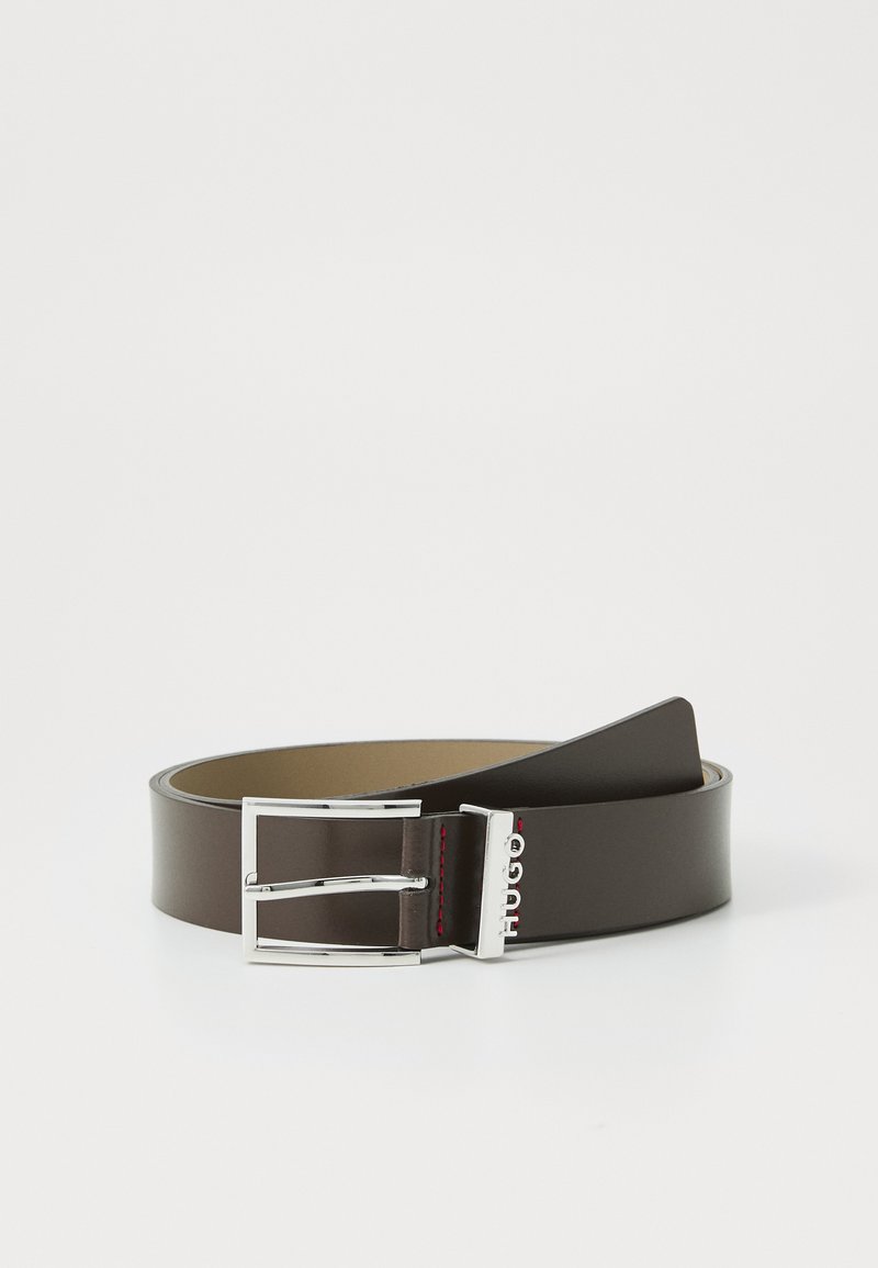 Ceinture en cuir marron avec une boucle en métal argenté, arborant un logo et des surpiqures rouges. Texture lisse et design classique.